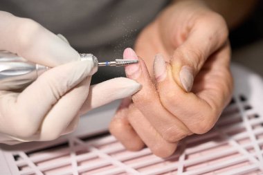 Tırnak matkabıyla manikür yapan bir kadın.