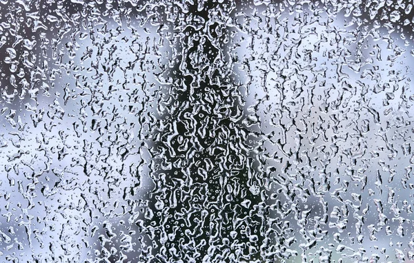 Texture of frozen water drops on the glass. Dark triangle silhouette on the background. — Stock Photo, Image