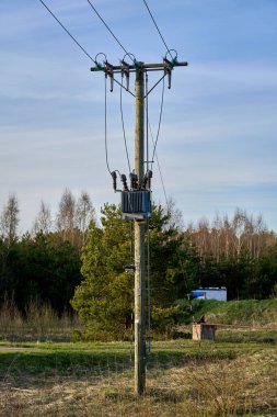 Eski ahşap bir elektrik direği elektrik kabloları ve mavi gökyüzü arka planlı kablolar.