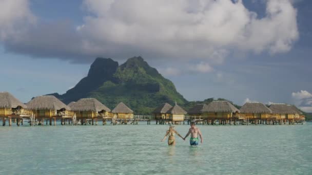 Para Trzymających Się Ręce Brodzących Oceanie Pobliżu Bungalowów Tahiti Bora — Wideo stockowe