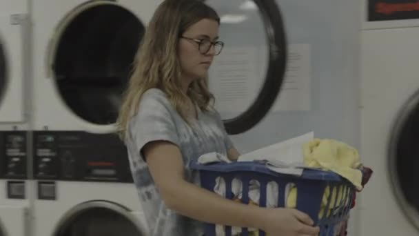 ランドリーマットで洗濯バスケットを持っている女の子と読書本 プロボ ユタ州 アメリカ — ストック動画