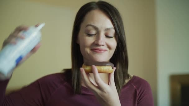 Lächelnde Frau Sprüht Schlagsahne Auf Schokoladen Donut Und Isst Ihn — Stockvideo