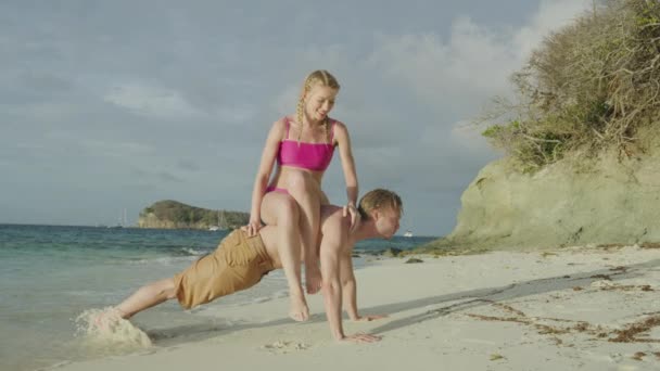 妇女坐在男子的背上做俯卧撑 然后倒在海滩上 圣文森特和格林纳丁斯 多巴哥礁 詹姆斯比岛 — 图库视频影像