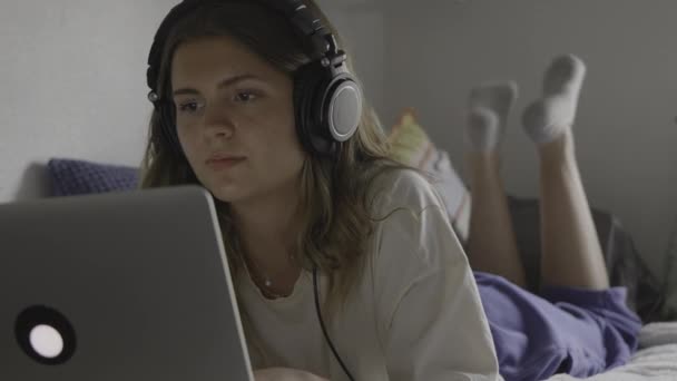 美国犹他州普罗沃市 躺在床上听耳机和打字的女孩 — 图库视频影像