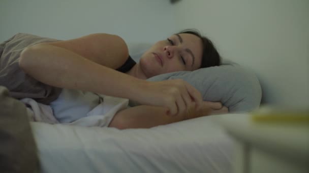 アメリカ ユタ州 マレー語でフラストレーションのあるテキストメッセージをチェックするために目が覚めるベッドの中の女性 — ストック動画