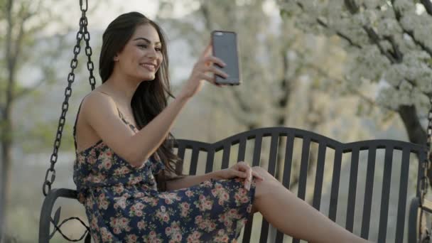Medium Slow Motion Shot Woman Video Chatting Bench Swing Cedar — Video Stock