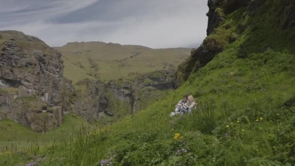 遠くの夫婦が丘の上に座って写真を撮る Evindarholar Iceland — ストック動画