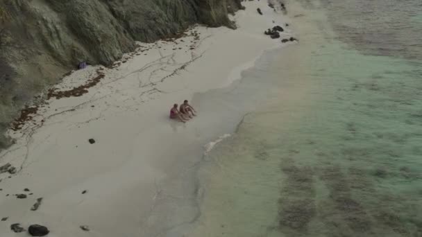 在圣文森特和格林纳丁斯靠近海浪 詹姆斯比岛的海滩上 一对夫妇坐在一起 空中放大 — 图库视频影像