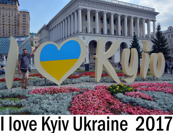 KYIV UKRAINE 09 03 17: I LOVE KYIV SIGN against the Independence Monument, Hotel Ukraine and Tchaikovsky's National Music Academy with flowers on the foreground at Maidan Nezalezhnosti 