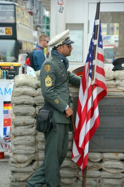 BERLİN, ALMANY - 08 23 17: Amerikan askeri gibi giyinmiş kimliği belirsiz genç adam Charlie 'nin soğuk savaşı hatırladığı kontrol noktasında duruyor