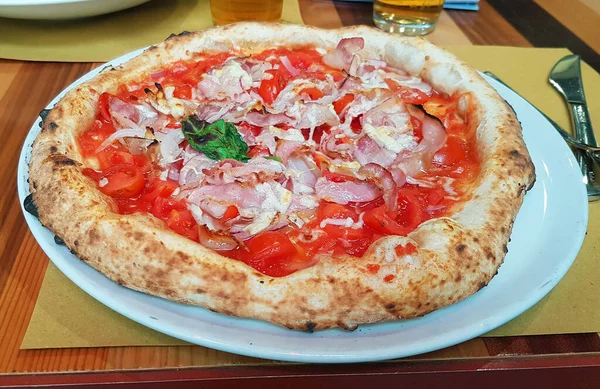 Close-up on a restaurant table pizza with prosciutto and parmesan cheese