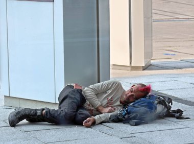 Sokak ortasında uyuyan evsiz bir adam.
