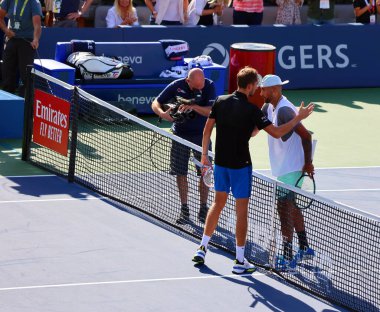 Profesyonel tenisçiler kortta sarılıyorlar.