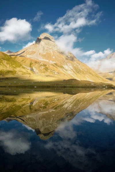 See mit Bergen und Wolken, die sich auf dem Wasser spiegeln. Ruhige Naturlandschaft. See mit ruhigem Wasser und Spiegelungen Stockbild