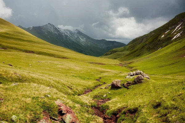 Hegyi patak folyik át a köveken egy zöld völgyben a hegyek között. Karachay-Cserkijeszija — Stock Fotó