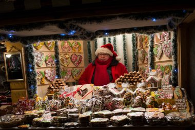 Riga, Letonya 15.12.2012 Kış Akşamı. Akşam sokak lambalarıyla aydınlatılmış. Noel 'den önce, Yılbaşından önce. Hediyelerle dolu küçük bir kulübe, Noel pazarında süslemeler, ladin dalları ve ampullerle süslenmiş.. 