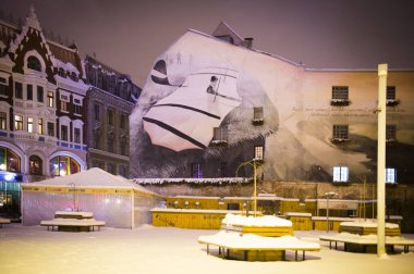 Riga, Letonya 15.12.2012 Kış akşamı sokak lambalarıyla aydınlatıldı. Karlı sokaklar. Riga, Letonya. Web siteleri, broşürler, posterler, baskı ve tasarım için kullanılabilir.