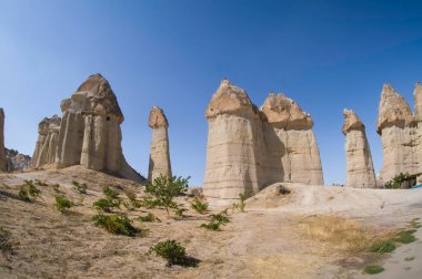 Beyaz Vadi Goreme, güneş, mavi gökyüzü, kayalar, beyaz kum, süslü ağaçlar, sevimli ahşap eşek. Ulusal desenli renkli halılar. 
