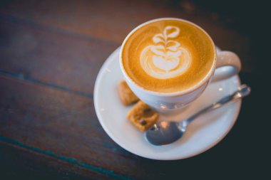 Tahta bir masada köpüklü sütlü kahve resmi.