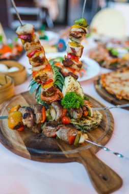 Şişte et barbeküsü ve lüks yemek masasında çeşitli sebzelerle süslenmiş.