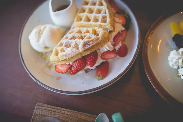 Picture of waffle pancake desert with vanilla ice cream, fresh strawberry and honey syrup