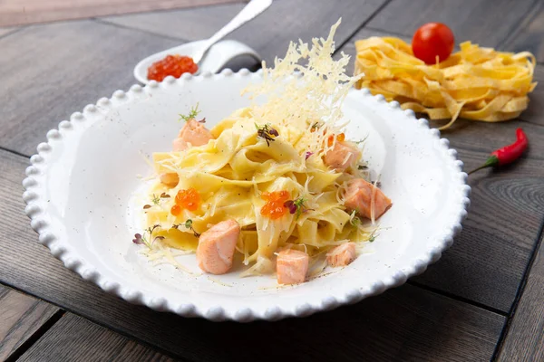 Salmon pasta in a plate. On a wooden background. Selective focus