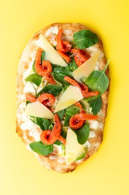 Somon, peynir ve otlu Roma pizzası. Sarı arka planda.