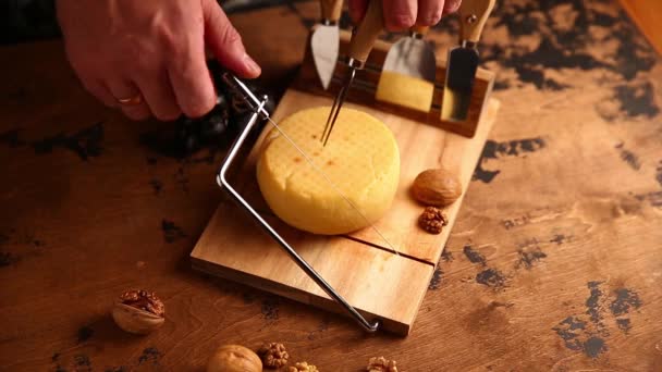 手で硬いチーズを紐で切る 木のテーブルの上で — ストック動画