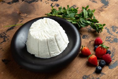 Ricotta cheese in a plate. On a wooden table. Selective focus.