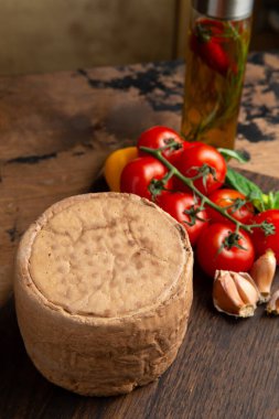 A small head of cheese. On a wooden table. Selective focus.
