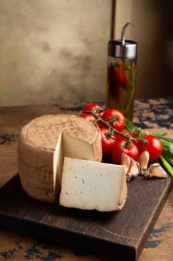 A small head of cheese and a cut piece. On a wooden table. Selective focus.