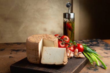 A small head of cheese and a cut piece. On a wooden table. Selective focus.
