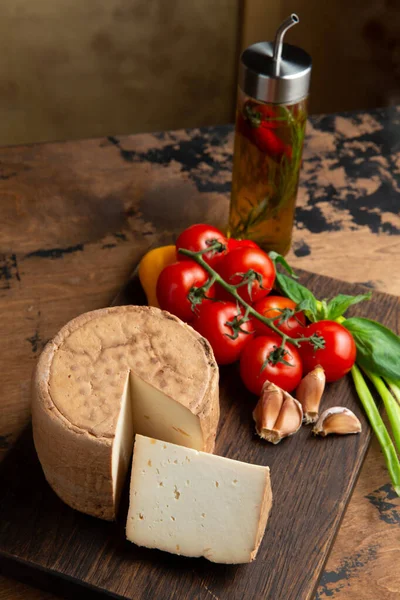 A small head of cheese and a cut piece. On a wooden table. Selective focus.