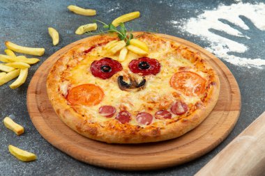 Homemade pizza in the form of a smiley On a gray background. Selective focus.