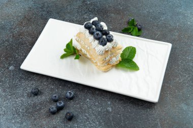Dessert with blueberries and whipped cream. On a gray background.