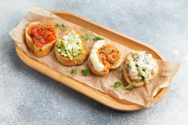 Assorted bruschettes on a wooden plate. Selective focus.