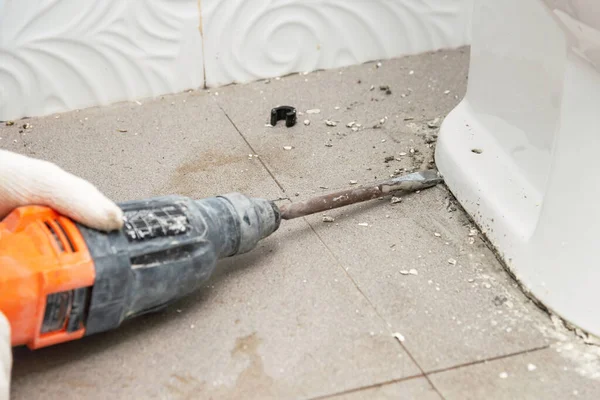 İşçi tuvaletteki boruyu tamir etmek için klozetin tamiri yapıyor.