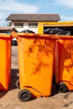  Halka açık bir yerde turuncu çöp kutusu. Çevreyi temiz ve rahat tutmak için gerekli malzemeler, Turuncu Plastik Atık Konteynırı veya Wheelie Bin.