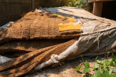 Çimlerin üzerinde eski bir yatak, unutulmuş, paslı, kirli, yırtık eski bir döşek, sokağa atılmış eski bir döşek. Evsizlik ya da yoksulluk