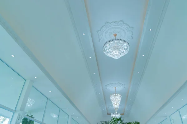 A large beautiful crystal chandelier in the living room against a white ceiling. lamp in the interior