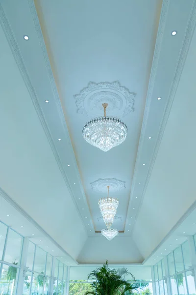A large beautiful crystal chandelier in the living room against a white ceiling. lamp in the interior