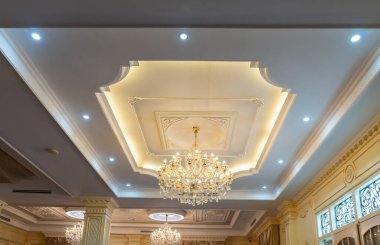 Oturma odasında beyaz bir tavana karşı büyük, güzel bir kristal avize. İçerideki lamba.