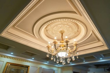 Oturma odasında beyaz bir tavana karşı büyük, güzel bir kristal avize. İçerideki lamba.