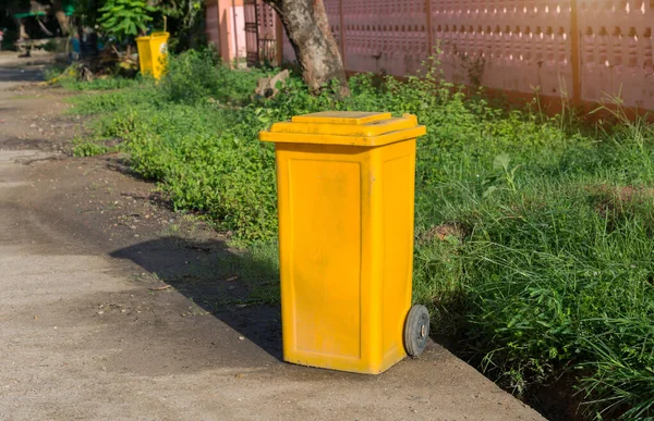Yellow trash cans are located in the park.