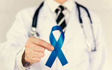 Doctor Holds Blue Ribbon, Colon cencer farkındalığı. Sembolik konsept farkındalığı artırma kaygıları Renksel kanser hastalığında yaşayan insanların kampanyasına yardımcı oluyor.