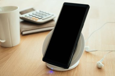 Mobil akıllı telefon kablosuz hızlı şarj cihazına yerleştirilir. Reklamınız için kırpma yolu olan boş ekran.