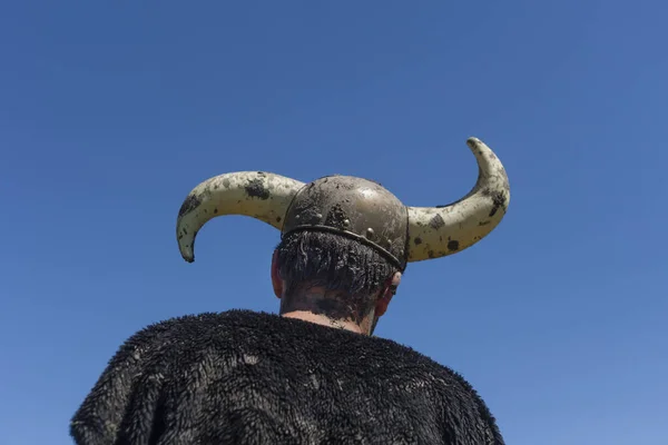 Boynuzlu oyuncak kasklı Viking gibi giyinmiş bir adam.