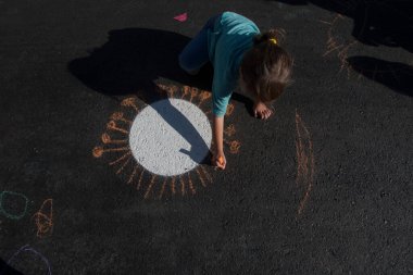 Bir kız asfalta tebeşirle koronavirüs çiziyor.