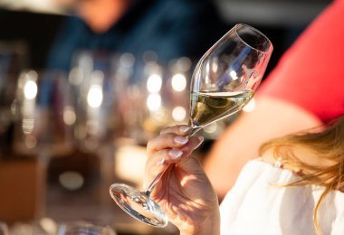 Sağ el, kristal bardağı beyaz şarapla tutar.