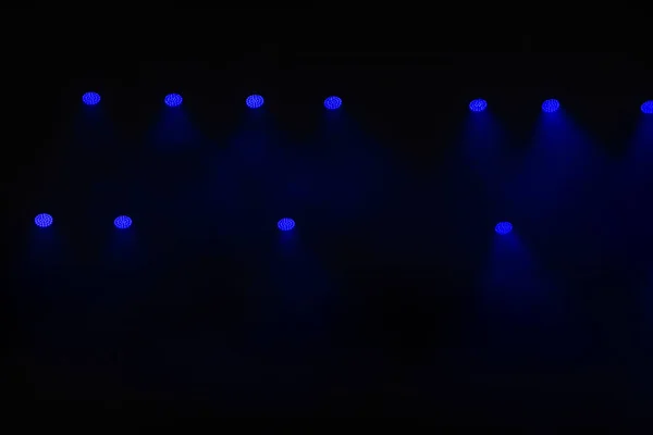 Stage lighting. Spotlights with colored lights on a stage. Artificial lighting. Black background and blur.